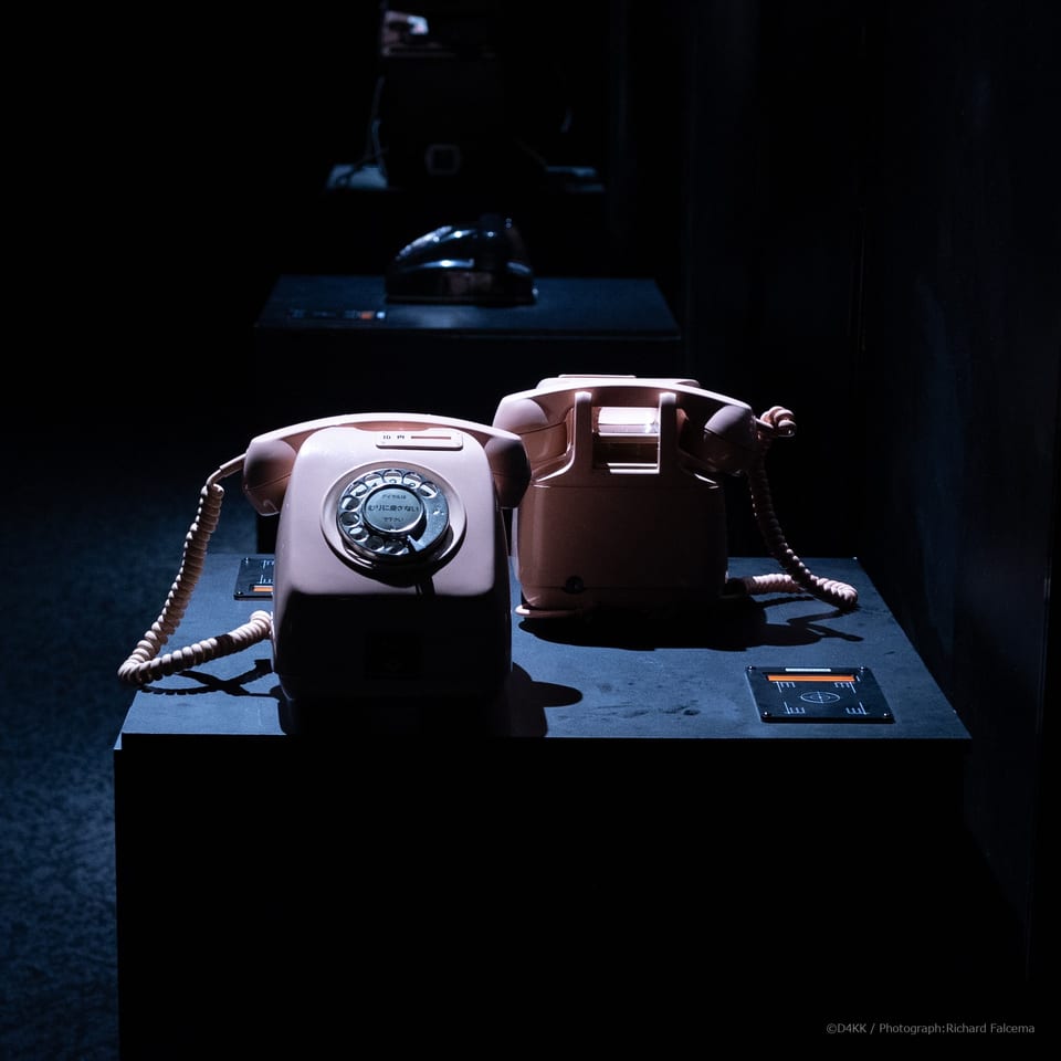 Two vintage rotary telephones displayed with custom card readers in the 050-5893-5336 exhibition