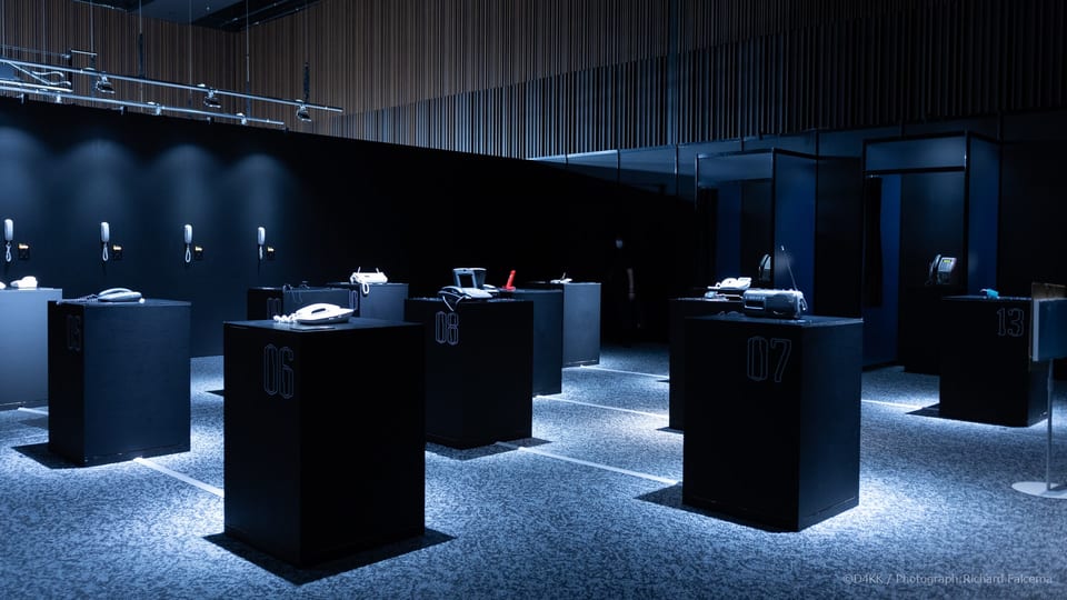 Overview of the 050-5893-5336 interactive telephone exhibition, featuring telephones from different eras arranged across the venue