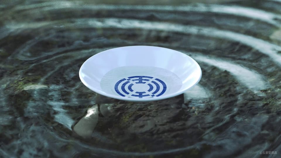 Sake cup featuring the GYOKUSENDO logo, placed on rippling spring water