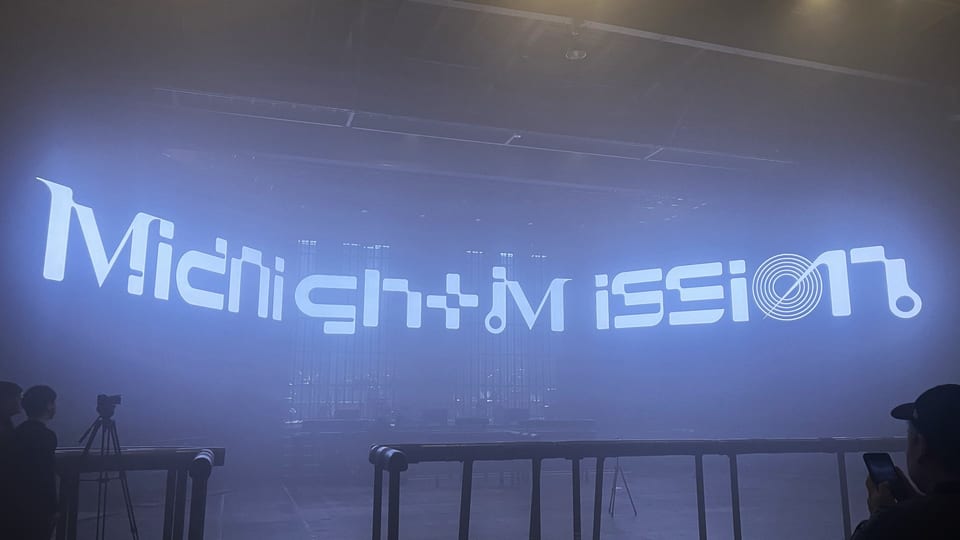 Midnight Mission live performance with the Midnight Mission logo displayed on the large screen
